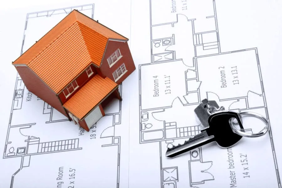 A model home and house key on architectural floor plans for an extension